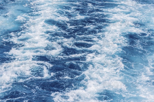 Turbulent sea waves with foam and ripples in deep blue water. The movement captures the raw power of the ocean