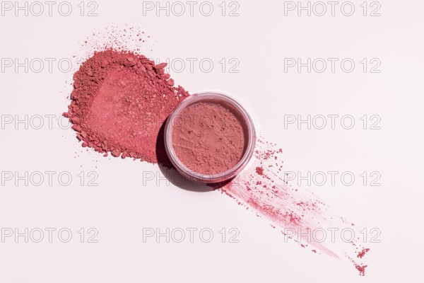 A pink blush powder elegantly spread out on a light backdrop, with an open container This image highlights the texture and vibrant color, ideal for beauty themes