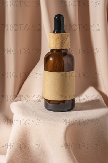 A stylish amber glass dropper bottle with a wooden cap rests gracefully on soft beige fabric Perfect for cosmetics or essential oils Elegant and minimalist design