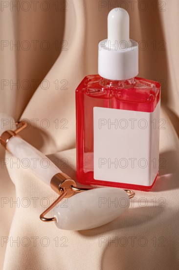 Close-up of a red serum cosmetic and a jade roller on soft beige fabric The composition highlights beauty and skincare essentials for a stylish self-care routine