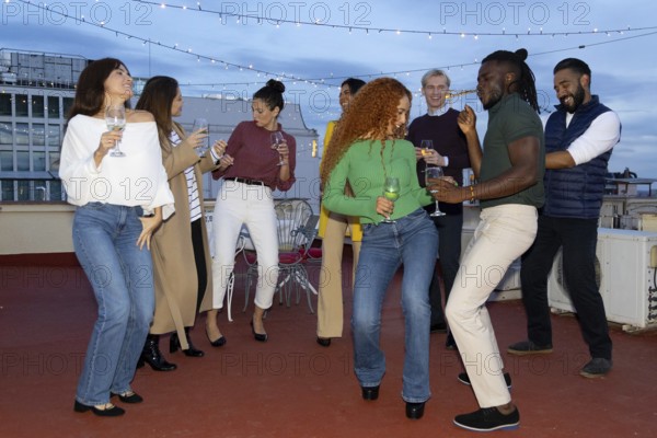 A lively group of friends celebrating on a rooftop, enjoying music and drinks They dance and laugh under string lights, creating a festive and joyful atmosphere