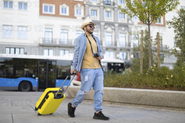 A stylish Latino transgender man strolls through the city with a camera and a vibrant yellow suitcase He embodies individuality, pride, and the spirit of adventure