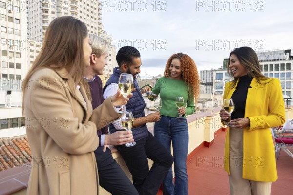 A diverse group of friends celebrates with drinks at a rooftop party in the city They are laughing and enjoying each other's company on a clear day
