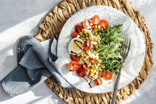 Delicious and nutritious keto salad featuring boiled eggs, fresh rocket, cherry tomatoes, canned green peas, and sprouted green beans, all drizzled with balsamic sauce