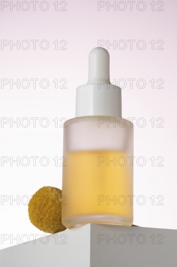 Elegantly displayed cosmetic serum bottle with a dropper, positioned on a geometric podium against a soft pink background, highlighting the product's sleek design and premium quality