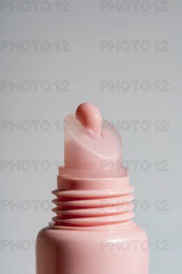 Close-up view of a pink lip balm on pink tube against a neutral background. This image showcases the texture and shine of the balm