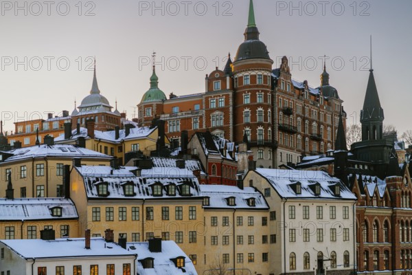 Discover the stunning architecture of Stockholm, Sweden, as the winter sun sets over snow-covered rooftops and historic buildings, highlighting their intricate designs