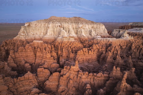 Captivating aerial view showcasing the striking, layered rock formations of Goblin Valley State Park, set against the expansive desert landscape in Utah, USA during the golden hour