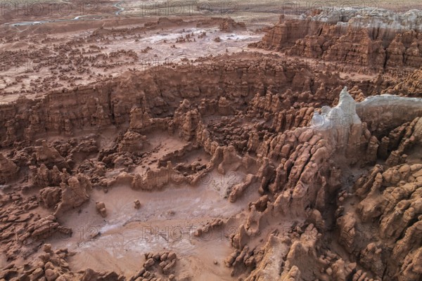 An aerial shot of Goblin Valley State Park in Utah, showcasing the park's unique, eerie geological formations and vast arid landscape under a dusky sky