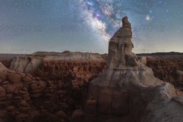 A breathtaking view of the Milky Way illuminating towering sandstone formations in Goblin Valley State Park, Utah, creating a mystical and serene night landscape