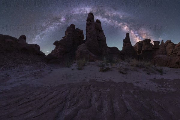 A mesmerizing night sky arches over unique sandstone formations in Goblin Valley State Park, Utah. The vibrant Milky Way complements the landscape's rugged beauty