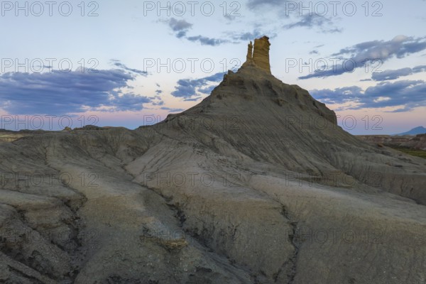 Majestic views of a unique rock formation against a vibrant sunset in Utah, capturing the serene yet rugged natural beauty of the area
