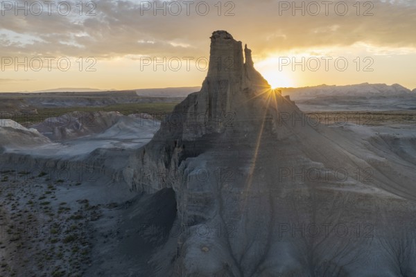 Breathtaking view as the sun sets behind a rugged peak in Utah, casting soft light over layered rock formations