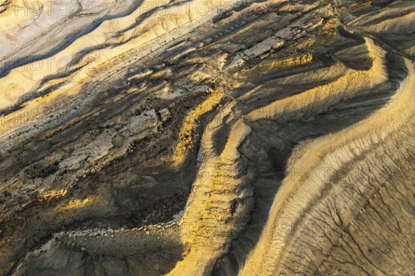 Aerial view of Utah's golden sandstone desert. Dramatic patterns and textures create a mesmerizing natural artwork. The sunlight enhances the rich colors and contours