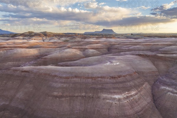 Majestic aerial view of striated Bentonite hills under a vast sky in Utah, showcasing the stunning natural landscape formations unique to the area