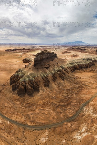 A majestic aerial perspective of Goblin Valley State Park, showcasing its stunning eroded rock formations, winding road cutting through the desert and vast, arid landscape under a cloud-filled sky in Utah, USA
