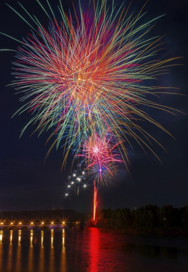 A stunning fireworks show illuminates the night sky above the Ebro River, casting vibrant reflections on the water