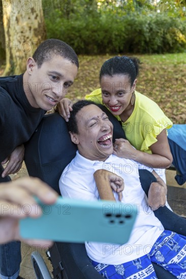 Two siblings pose for a joyful selfie with their disabled brother, who has cerebral palsy, enjoying a beautiful day outdoors and celebrating family togetherness