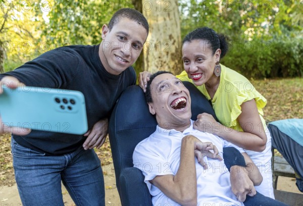 Two siblings pose for a joyful selfie with their disabled brother, who has cerebral palsy, enjoying a beautiful day outdoors and celebrating family togetherness