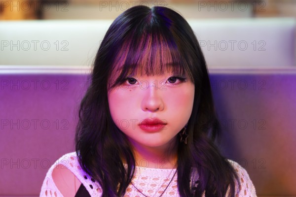 An Asian Gen Z girl is immersed in the vibrant atmosphere of an arcade Her expression reflects the excitement and energy of the colorful gaming environment