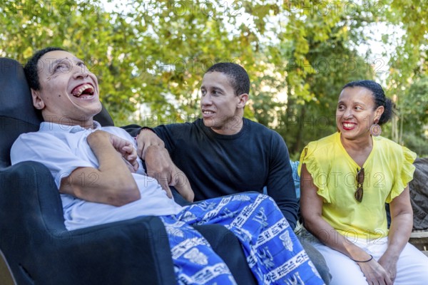 Spanish Cameroonian siblings outside, one with cerebral palsy, enjoying a sunny day together. This heartwarming family moment showcases diversity and unity