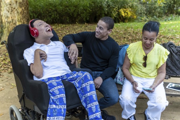 A Spanish Cameroonian family enjoying time outdoors. One sibling with cerebral palsy is engaged with others, highlighting Mixed-race unity and joy