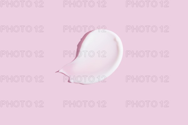 A high-quality image featuring a dollop of cosmetic cream smeared on a pastel pink background, ideal for beauty and skincare themes