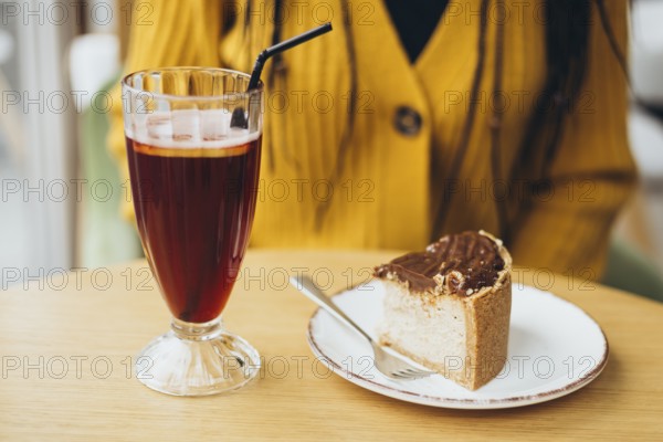 A cozy cafe scene with a refreshing iced coffee in a tall glass and a delectable slice of chocolate cake on a white plate, set on a wooden table with warm ambiance