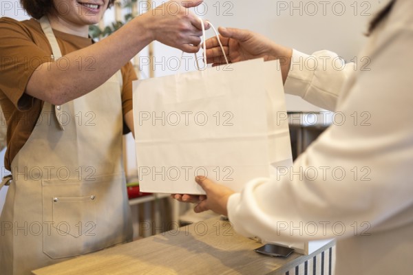 A friendly store employee hands a paper shopping bag to a customer The image captures a moment of positive customer service at a retail counter, emphasizing hospitality