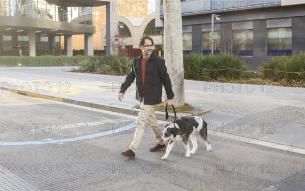 A man walks his dog through a busy city intersection, showcasing urban life and pet companionship in a modern setting