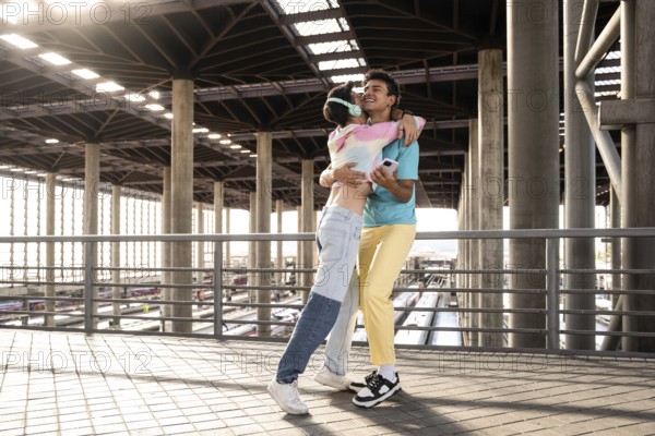 A joyful moment for a couple embracing each other at a train station. The sunlight filters through the architectural supports, highlighting their happiness