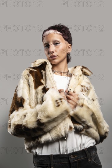 A woman with distinctive makeup and jewelry poses confidently in a stylish faux fur coat. The combination of accessories and makeup creates an edgy, modern look