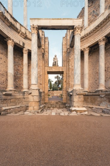 A stunning view of the Roman Theatre in Merida, highlighting its grand marble columns, ancient stone arches, and classical statue. This UNESCO World Heritage site reflects Roman architectural mastery
