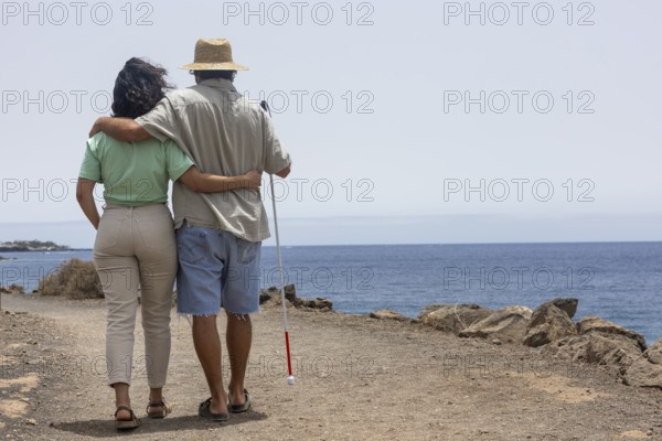 A blind man enjoying a seaside adventure with a companion. The image captures a serene moment, embodying travel, friendship, and the beauty of exploring new places