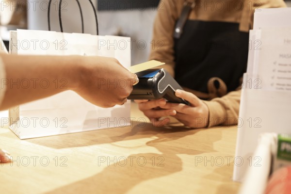 A customer makes a purchase using a point-of-sale terminal in a cosmetics store. A paper shopping bag is on the counter, showcasing a typical retail environment