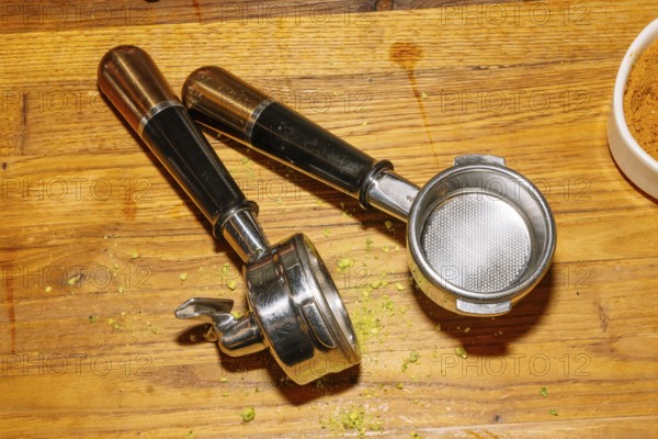 Two espresso machine portafilters rest on a wooden counter, displaying their metal baskets and handles
