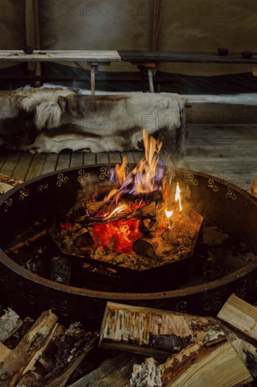 Warm and inviting fire in a Scandinavian setting in Swedish Lapland. Wooden logs are ready for burning, creating a cozy atmosphere