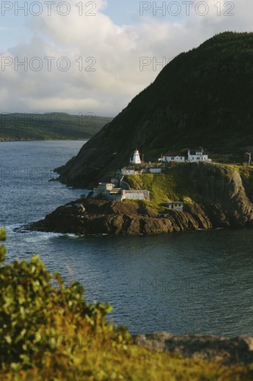 A picturesque Fort Amherst from atop Signal Hill, St. John's sits on the rugged coastline in Newfoundland & Labrador, bathed in the warm glow of the sunset. This tranquil scene captures the serene beauty of the Canadian seaside