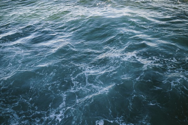 Close-up of dynamic ocean waves with swirling patterns and frothy textures at Flatrock, Newfoundland & Labrador, Canada. This image showcases the natural beauty and power of the sea