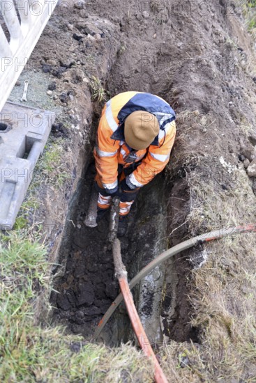 Technician connects fiber optic cable in the ground, Schleswig-Holstein, Germany