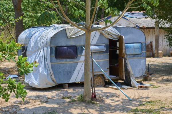 An outdated blue caravan stands in shade under trees in a rural setting, Pantanal, Mato Grosso, Brazil