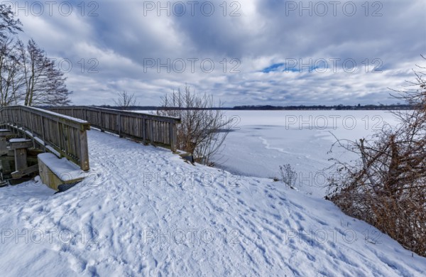 View of the Schaalsee, covered with ice and snow, on the bridge tour, a hiking trail with a wooden bridge around the church lake, in the UNESCO Schaalsee Biosphere Reserve. Zarrentin, Mecklenburg-Western Pomerania, Germany