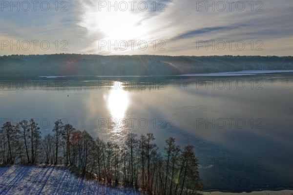 The sun reflects on Lake Werbellin in the UNESCO Schorfheide-Chorin Biosphere Reserve in winter. aerial view. Joachimsthal, Schorfheide, Brandenburg, Germany