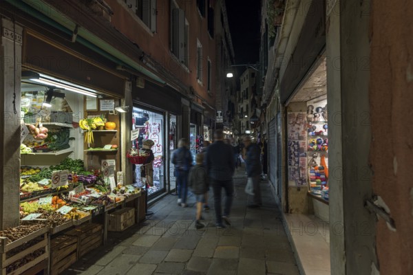 Old town alleyway at night with open vegetable shop, Venice, Veneto, Italy