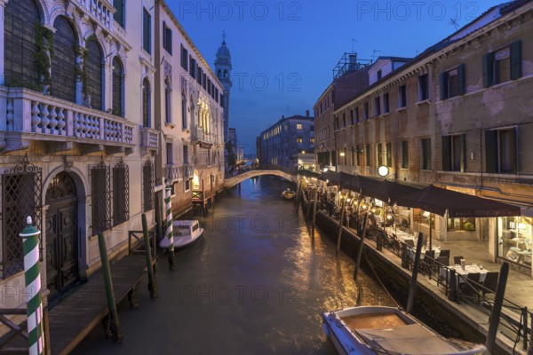 Dinner with restaurant on the canal, in the back the tower of the church of Santa Maria della Pietà, Venice, Veneto. italy
