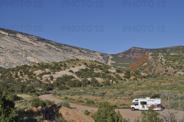 An RV parks in a picturesque mountain landscape with clear skies, Dinosaur National Monument, Utah, USA