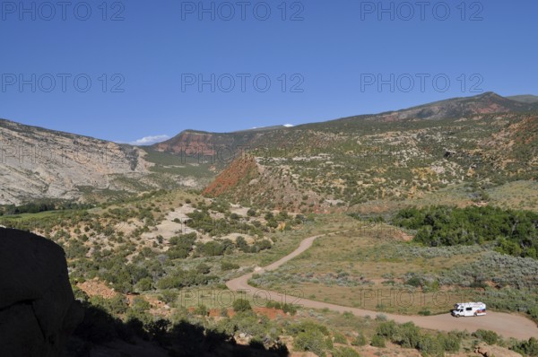 View of a valley with an RV on a road surrounded by mountains, Dinosaur National Monument, Utah, USA