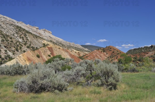 Rocks with colorful soil, vegetation and blue sky in hilly landscape, Dinosaur National Monument, Utah, USA