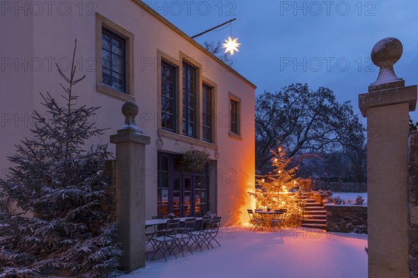 Illuminated Christmas tree and Herrnhut star in the snow at the Aust winery in Radebeul, Saxony, Germany