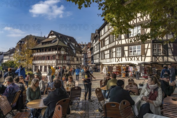 Busy cafe on Place Benjamin Zix and the Maison des Tanneurs timber-frame house in Petite France, Strasbourg, Alsace, France